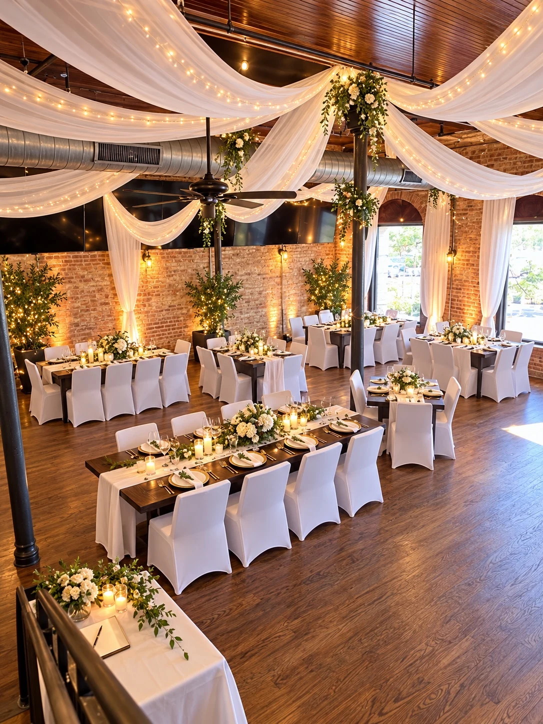 Uptown Hall arranged for a candlelit reception, with white drapery and floral greenery